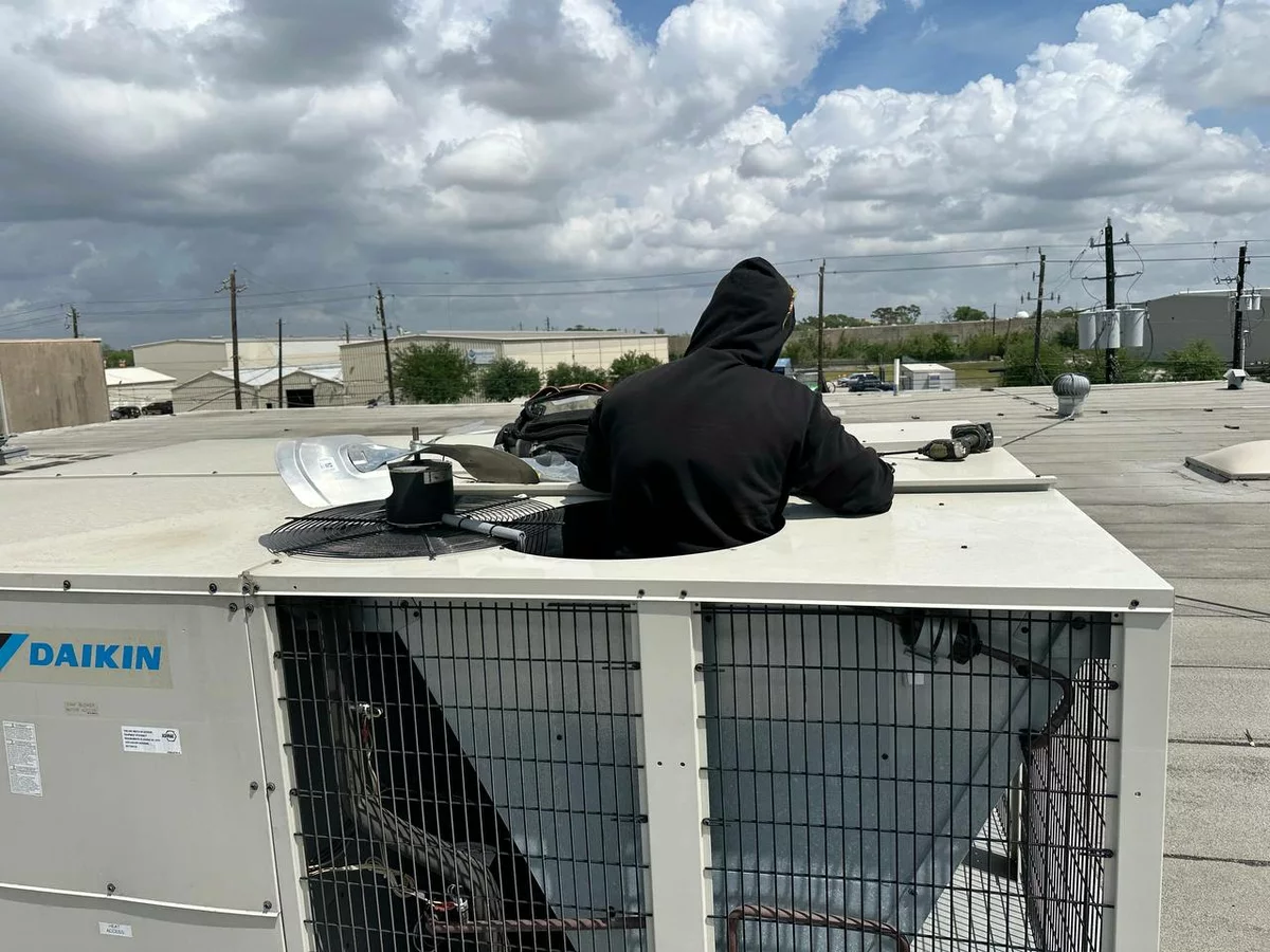 APCA technician servicing a commercial rooftop HVAC unit